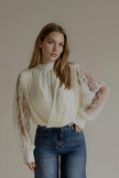 Blouse CAMILLE écrue à manches en dentelle portée avec un jean bleu, silhouette entière de face