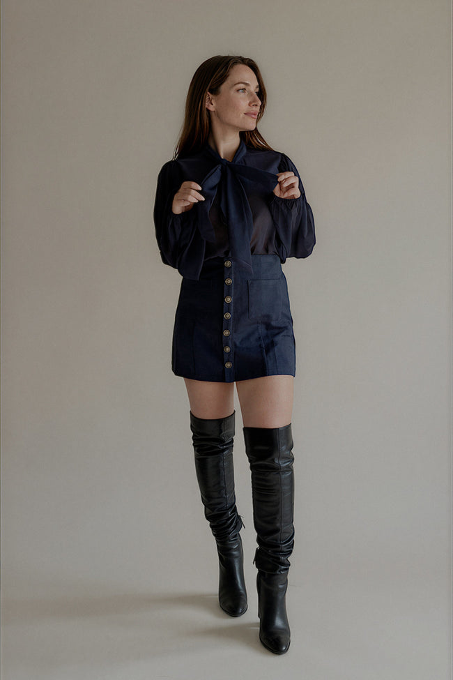 Chemise CASSANDRE bleu marine à col lavallière portée avec une jupe courte