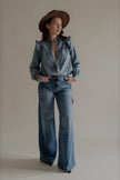 Chemise CLÉO en denim bleu à volants portée avec un jean large