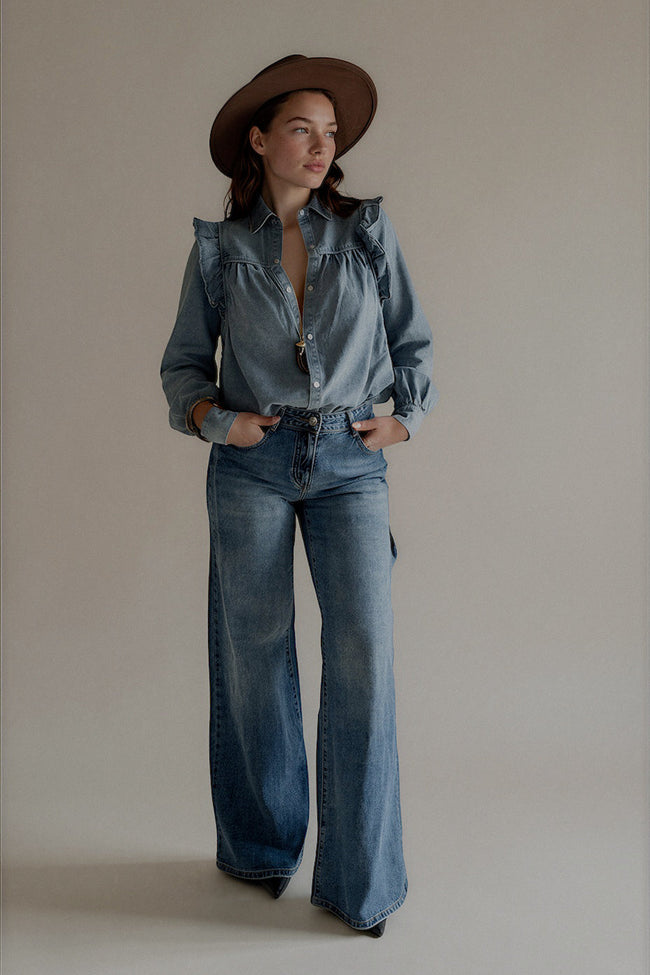 Chemise CLÉO en denim bleu à volants portée avec un jean large