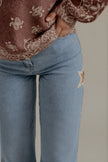 Détail du denim bleu clair et des découpes étoiles du jean POPPY