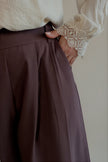 Détail du pantalon PIPPA marron – plis, taille haute et poche biais