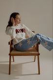 Jean POPPY bleu clair à découpes étoiles porté assis avec un sweat