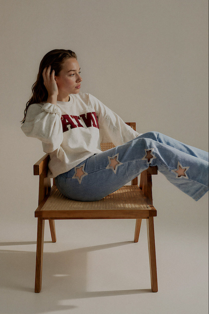 Jean POPPY bleu clair à découpes étoiles porté assis avec un sweat