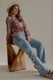 Jean POPPY bleu clair à étoiles porté assis avec le pull MARNIE