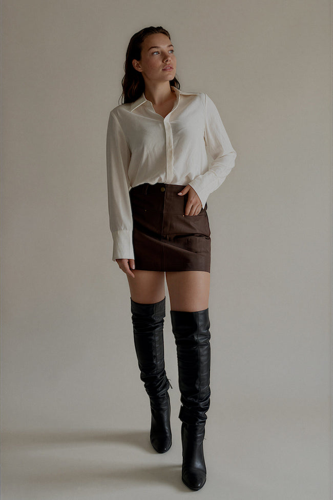 Jupe-short JOYCE marron effet cuir portée avec une chemise blanche, silhouette entière