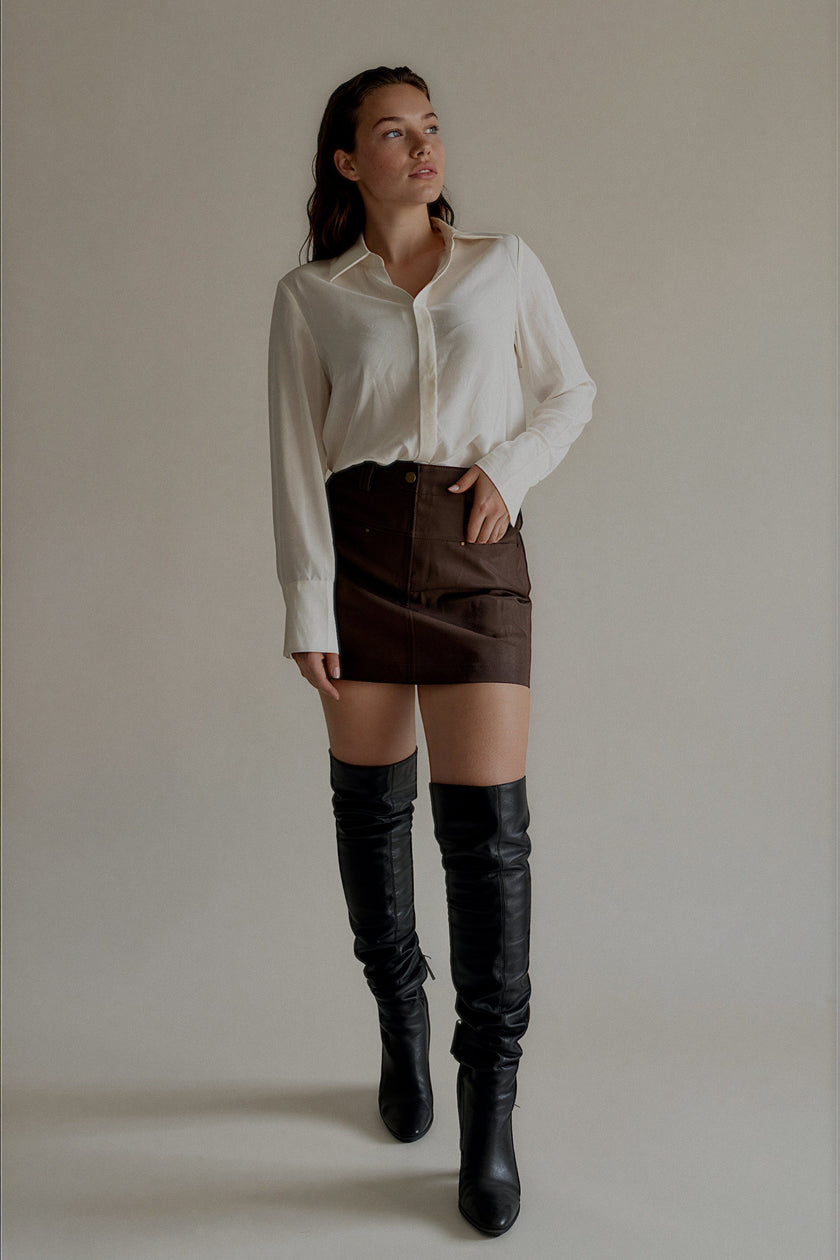 Jupe-short JOYCE marron effet cuir portée avec une chemise blanche, silhouette entière