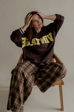 Pantalon PAULINE à carreaux marron porté assise avec un sweat marron