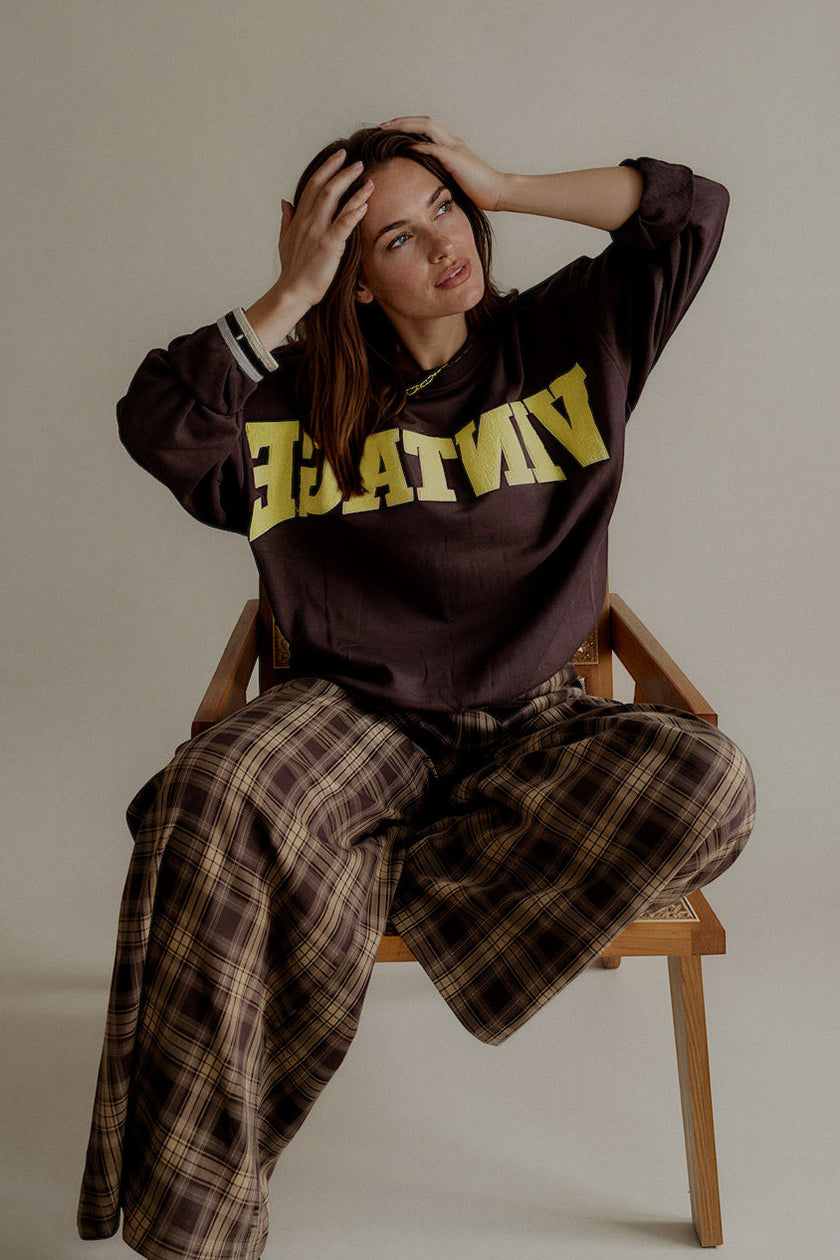 Pantalon PAULINE à carreaux marron porté assise avec un sweat marron
