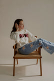 Sweat SIXTINE gris chiné à inscription bordeaux porté assis avec un jean clair