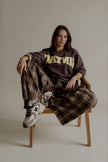 Sweat SIXTINE marron à inscription jaune porté avec un pantalon large à carreaux