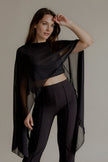 Top THÉA noir transparent à la coupe asymétrique porté avec un pantalon noir