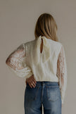 Vue de dos de la blouse CAMILLE écrue portée avec un jean bleu à strass