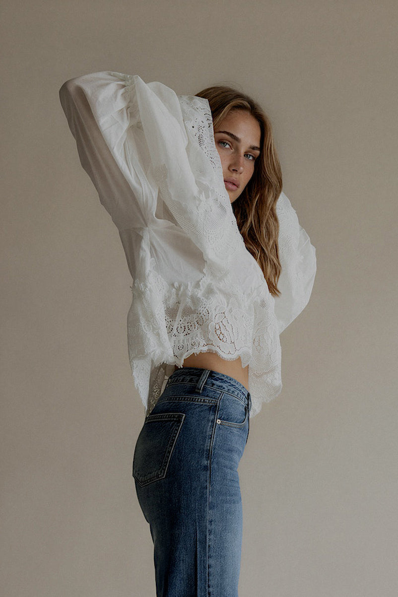 Vue de profil de la blouse CAPUCINE blanche ample à broderies portée avec un jean bleu