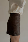 Vue de profil de la jupe-short JOYCE marron effet cuir portée avec des bottes hautes