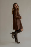 Vue de profil de la robe ROMY courte marron portée avec des bottes